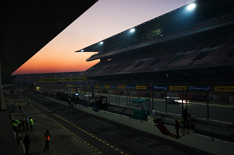 Solen står op over Dubai Autodrome, imens at Martin Sally sidder bag rattet yderst til højre i billedet.